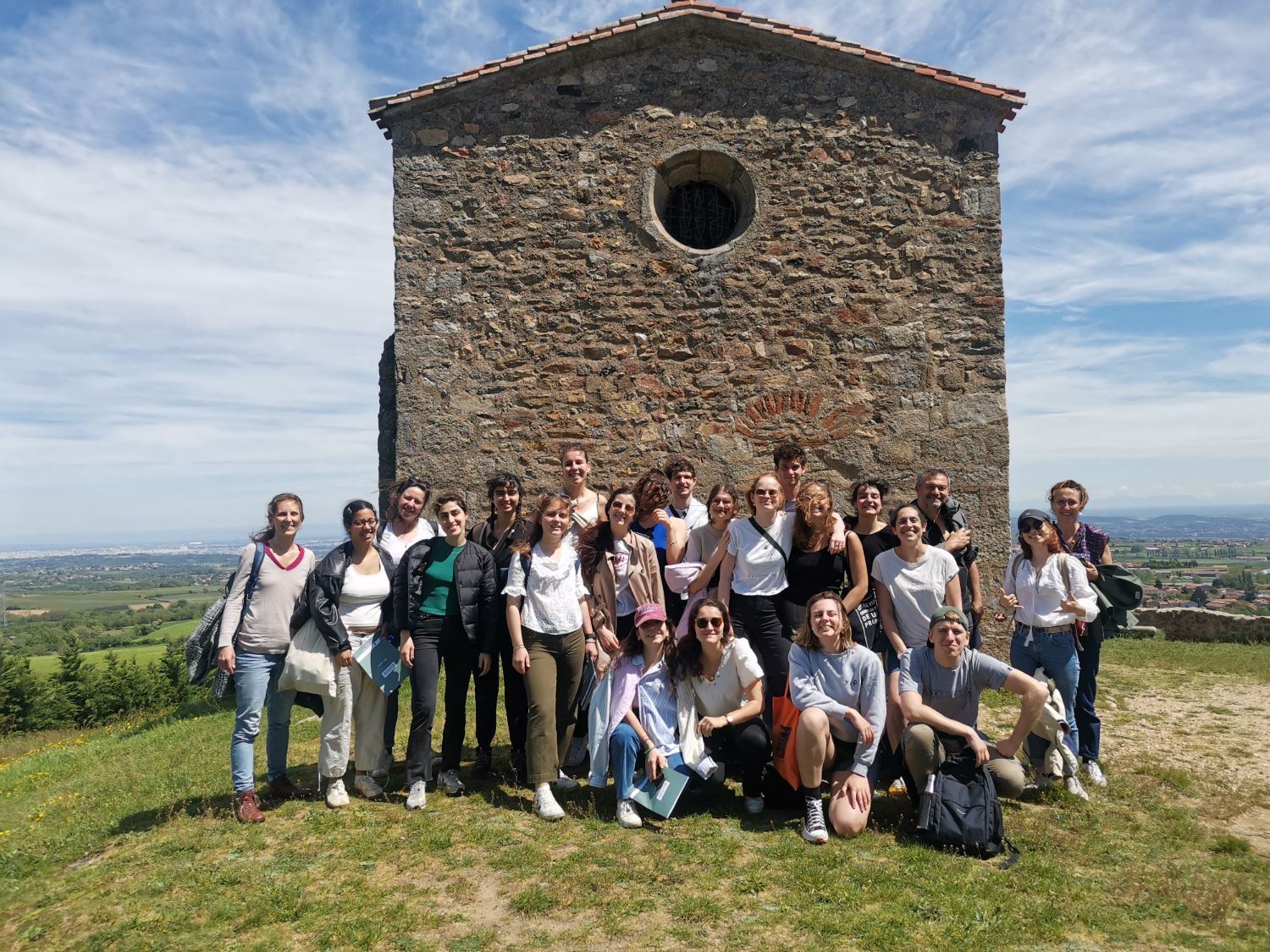 Un groupe réuni devant une chapelle en pierre, dominant la plaine
